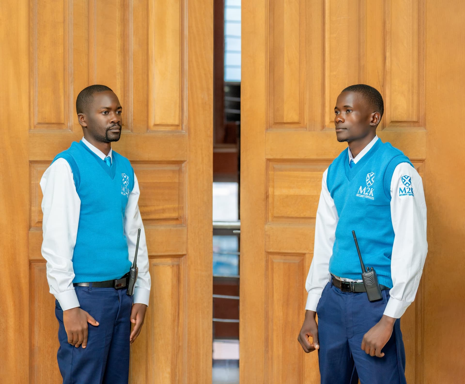 M2K guards standing watch at a doorway in branded uniform